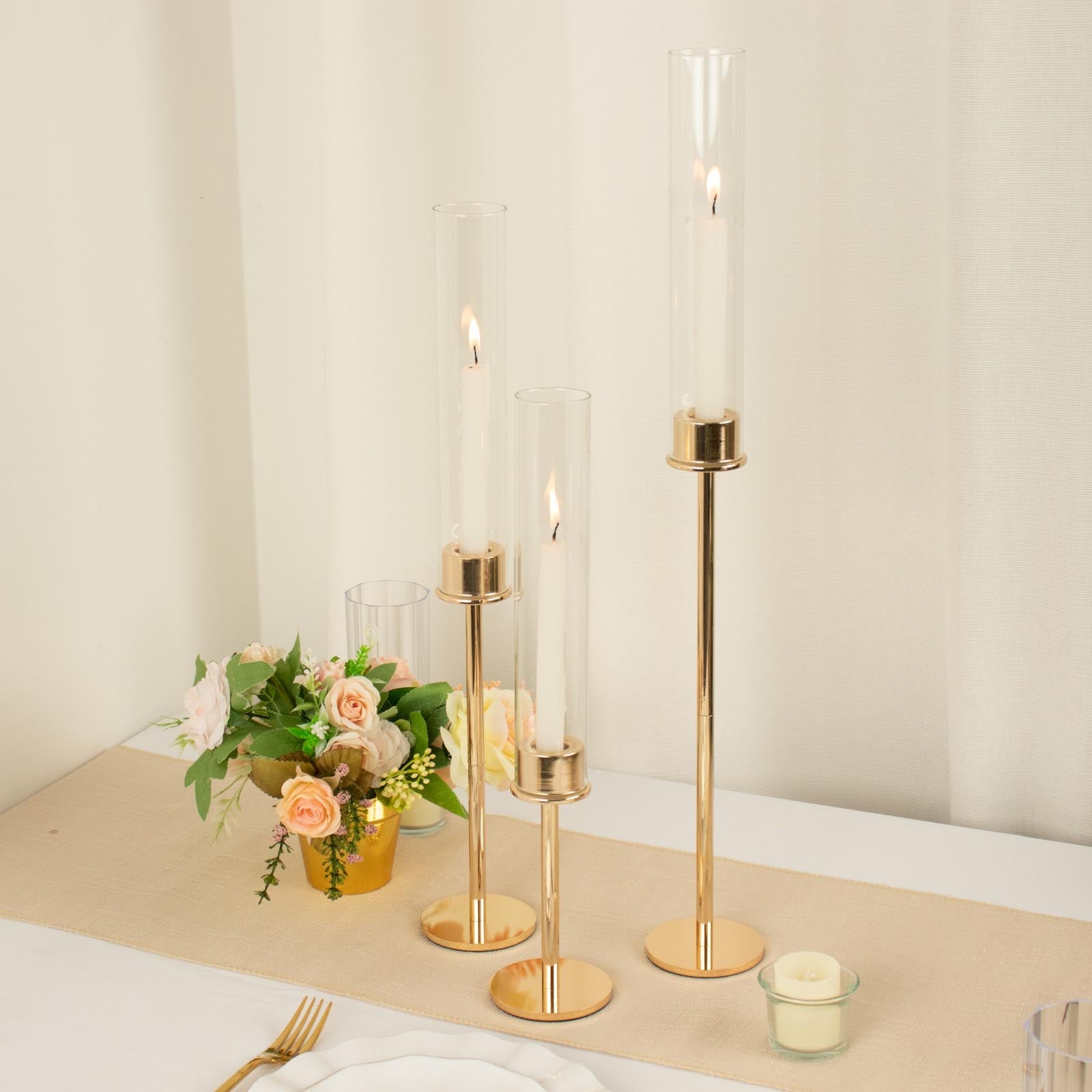 Tall gold metal candlestick holders with clear glass shades, 16", 20", and 24".