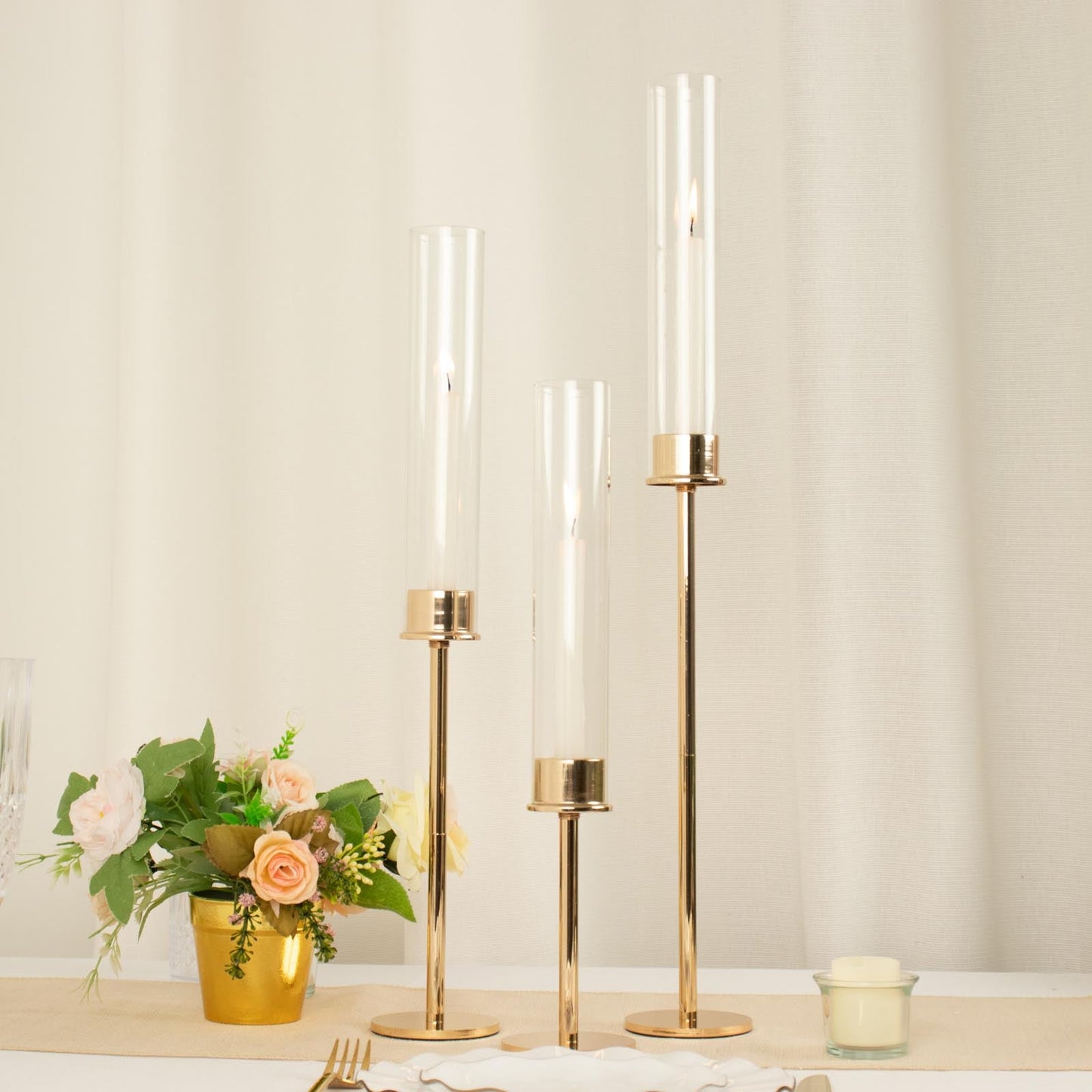 Tall gold metal candlestick holders with clear glass shades.