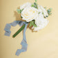 Dusty blue chiffon ribbon with bouquet of white roses on a yellow background.