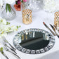 Silver jeweled rim glass mirror charger plates on a table setting.