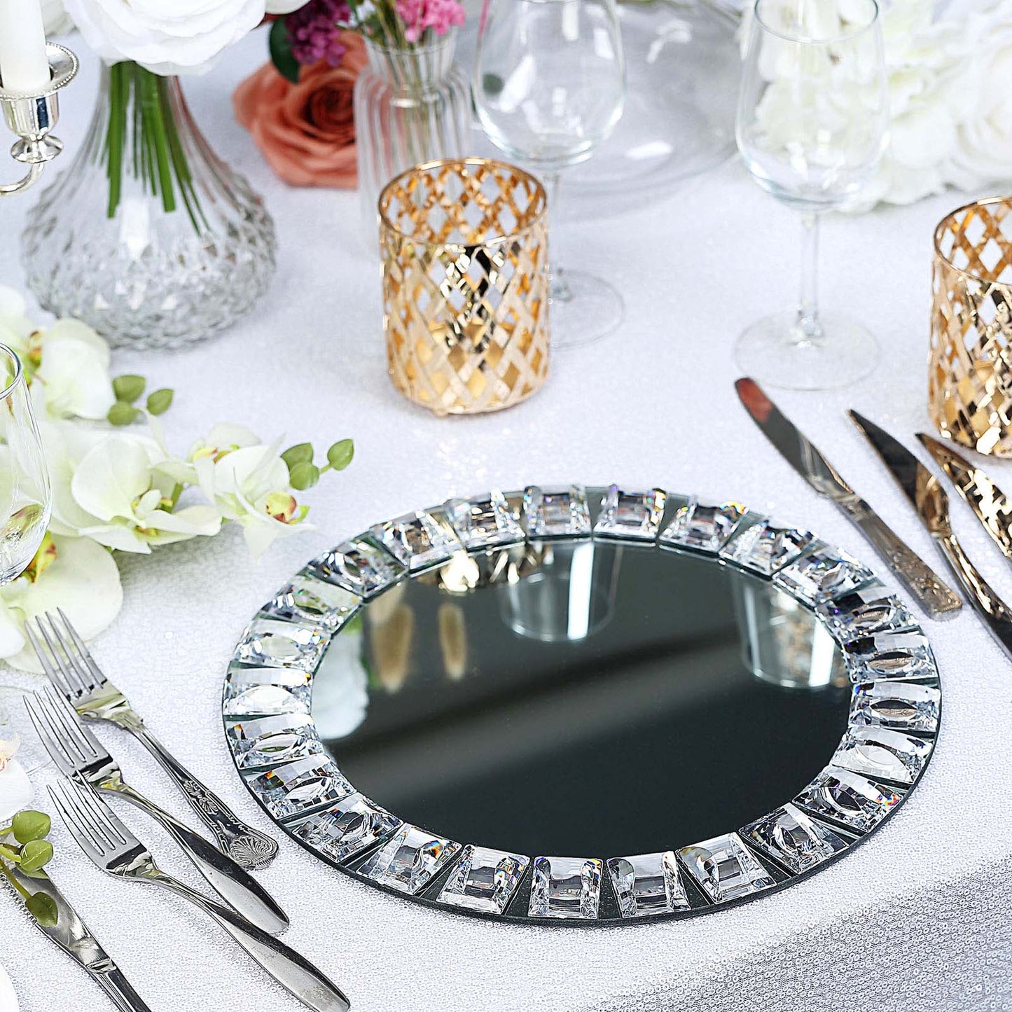 Silver jeweled rim glass mirror charger plates on a table setting.