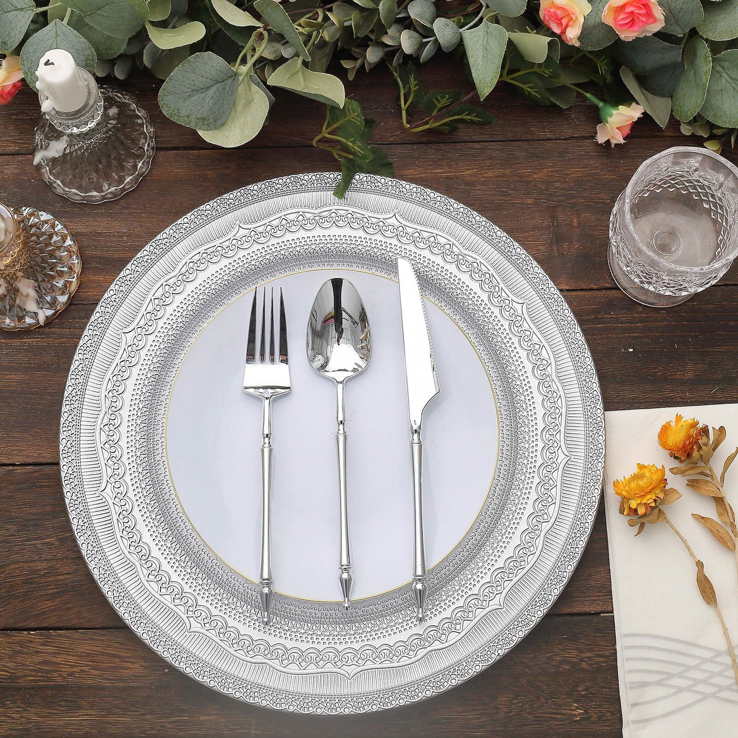 Silver rustic lace embossed acrylic charger plates on a wooden table.