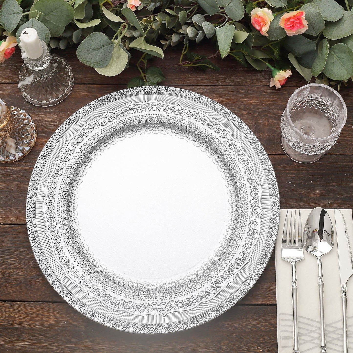 Silver rustic lace embossed acrylic charger plates on a wooden table.