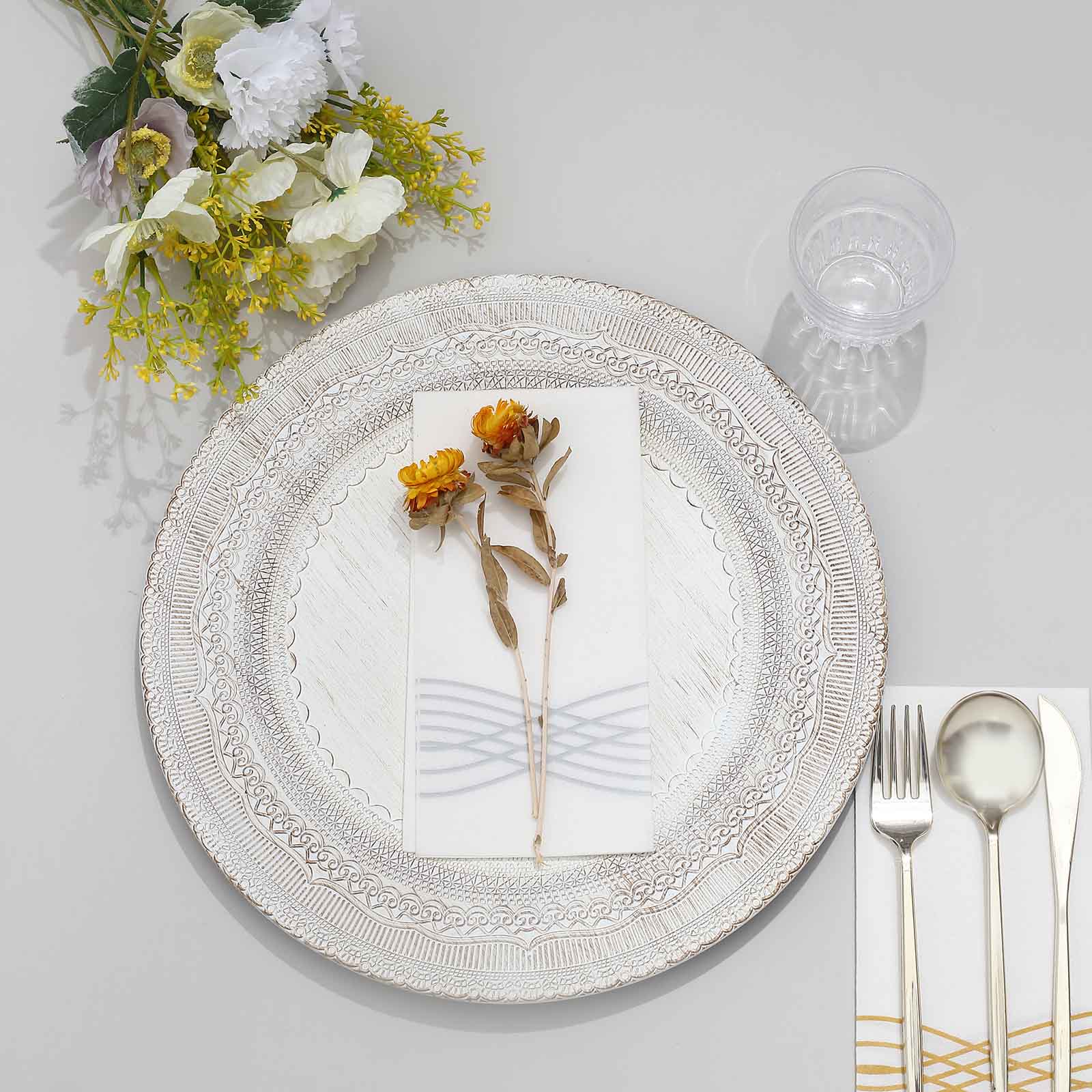 Elegant white dinner plate setting with flowers, glass, and silverware. Perfect for dining.