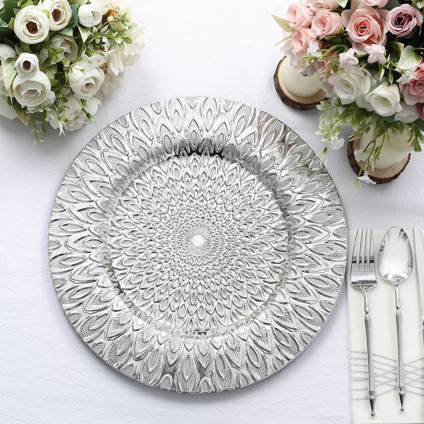 Silver embossed peacock design disposable charger plate on a table setting.