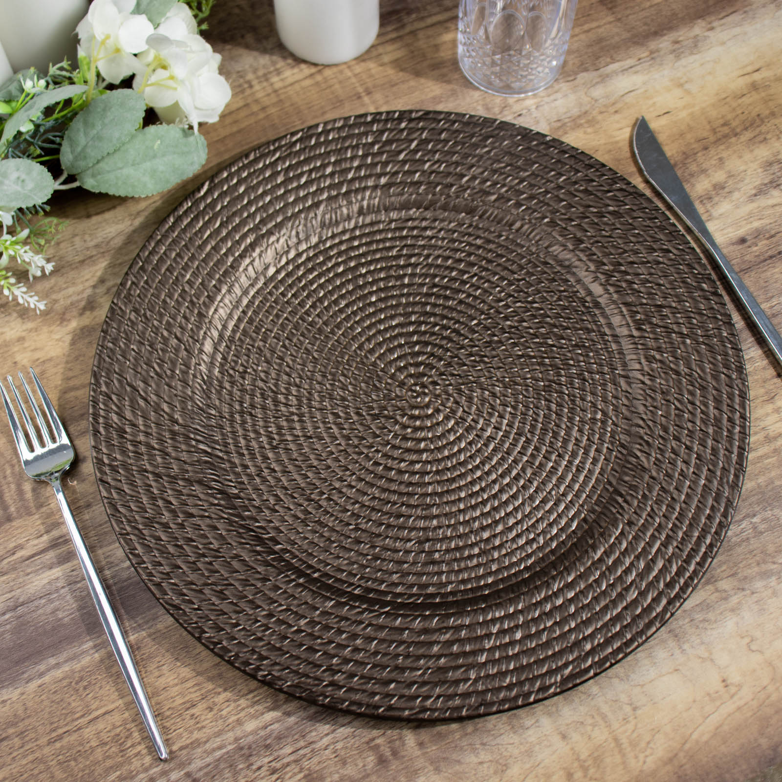 Natural brown rattan-like disposable round charger plate on a wooden table.