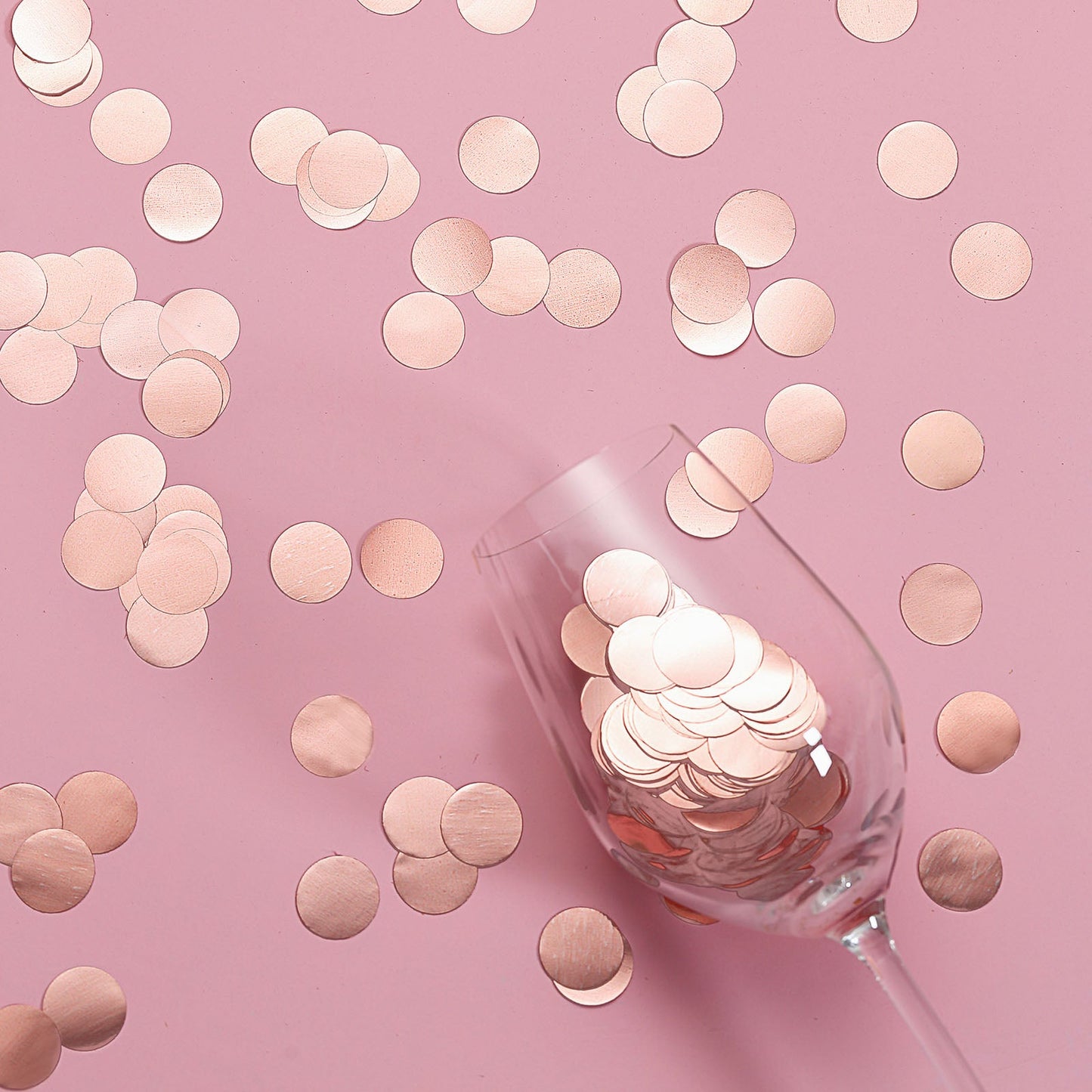 Rose gold round foil confetti dots on a pink background.