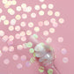 Iridescent round foil metallic confetti dots on pink background.