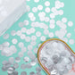 Silver round foil metallic table confetti dots on a mint green surface.