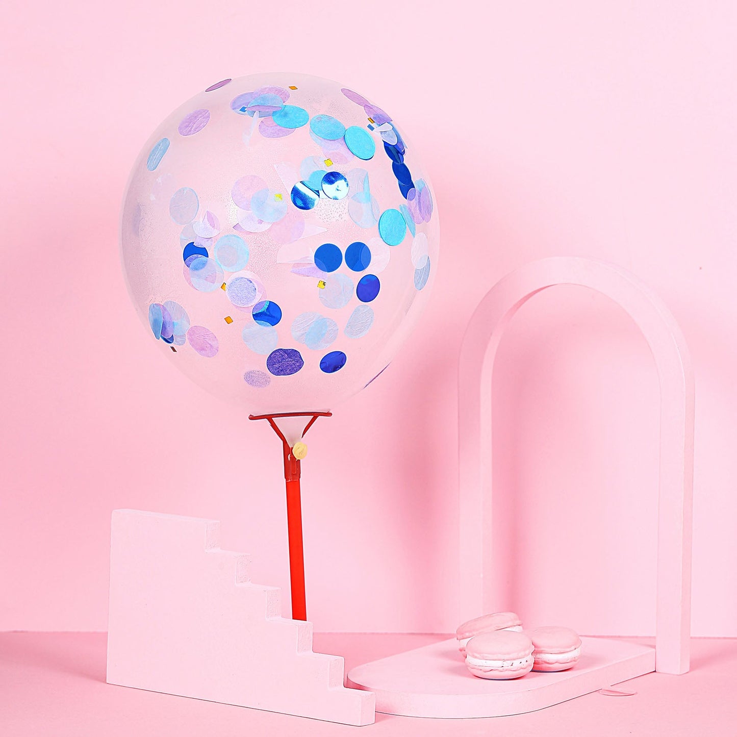 Purple and blue confetti balloon on a pink backdrop.