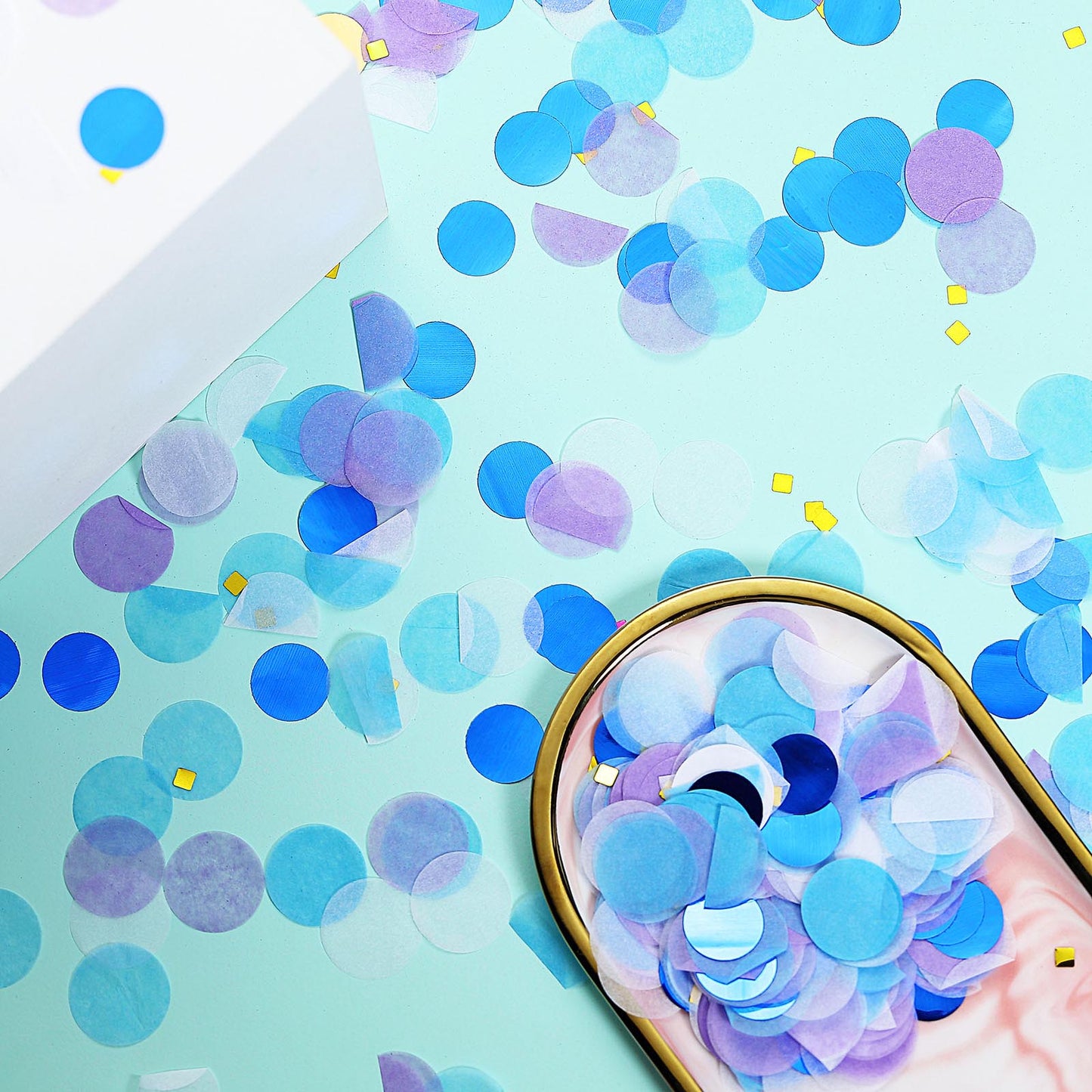 Purple and blue tissue paper and foil confetti mix on a mint background.