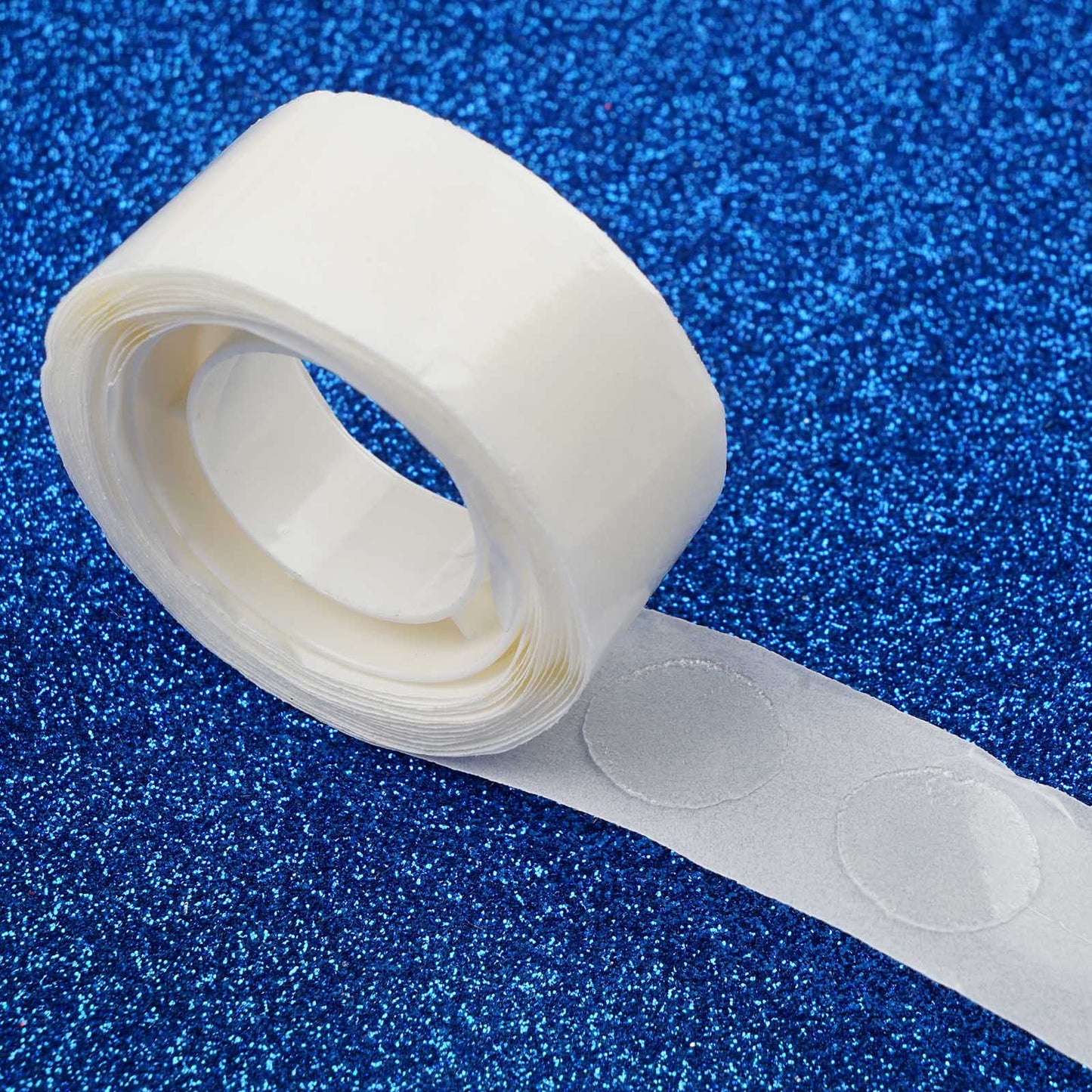 Clear adhesive dots for balloon arches on a blue background.