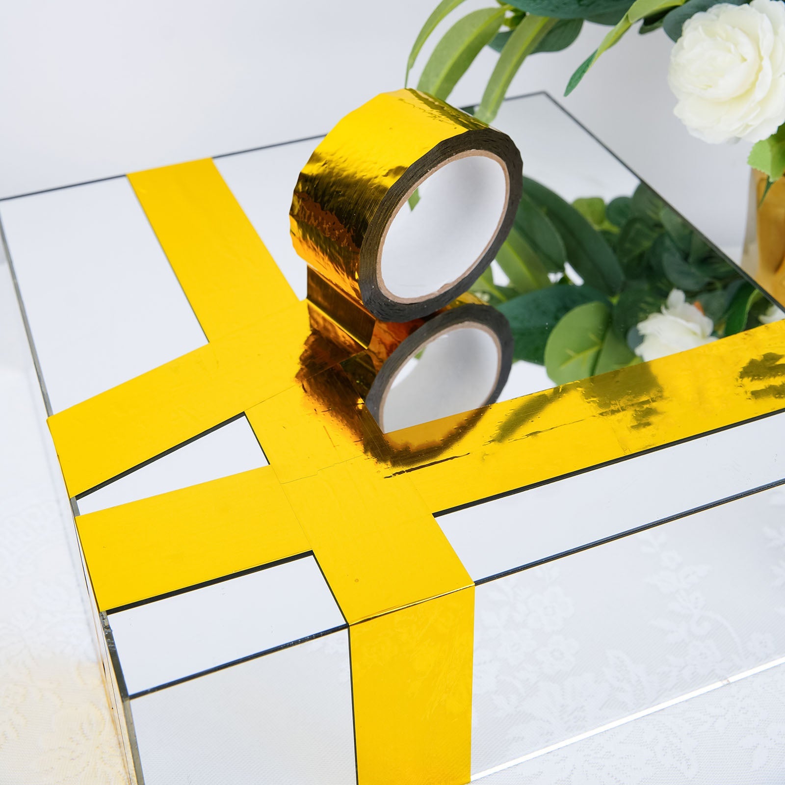 Gold metallic tape for crafts and floral decor on a reflective surface.