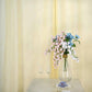 Ivory faux linen curtains with chrome grommets and floral arrangement.