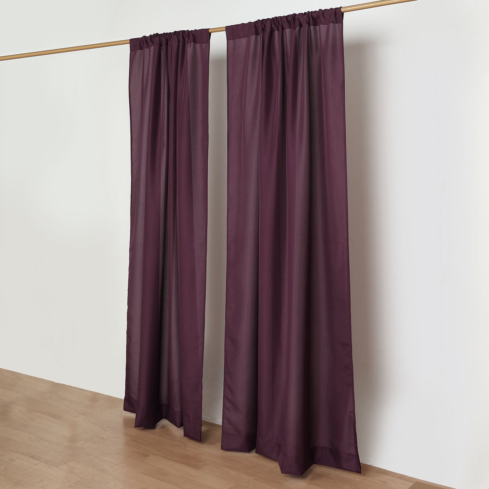 Eggplant polyester backdrop drape curtains on a rod.