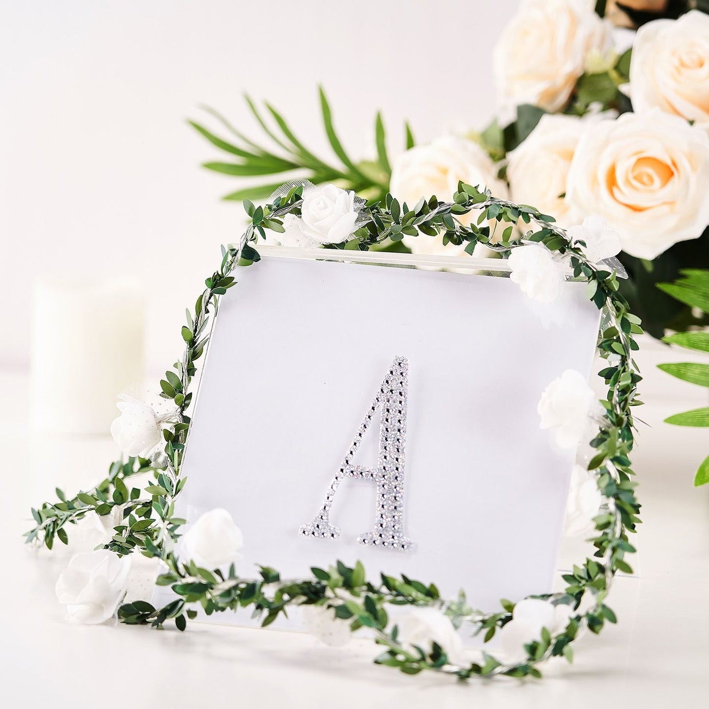 Silver decorative rhinestone letter "A" surrounded by floral frame.