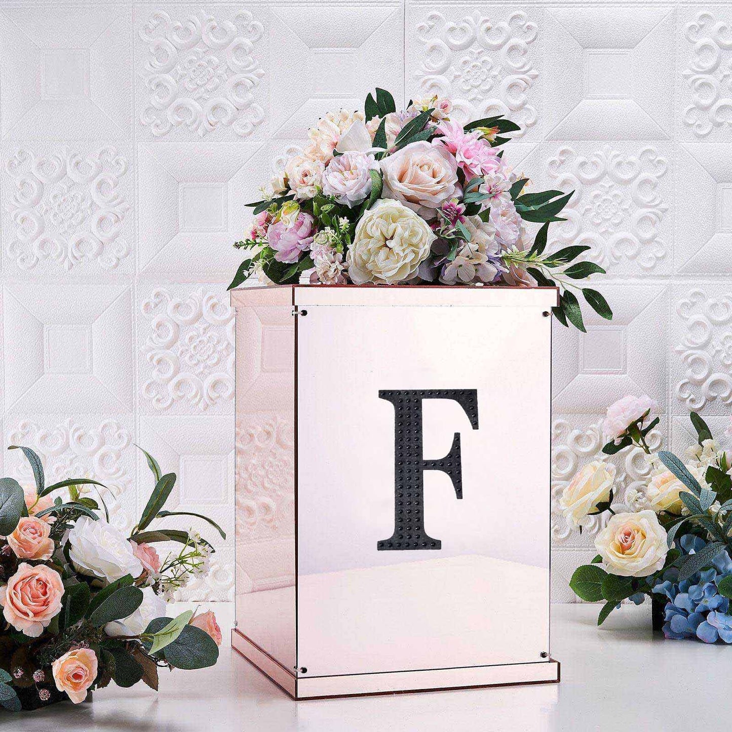 Black decorative rhinestone letter "F" on a floral arrangement.
