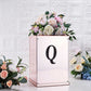 Black decorative rhinestone letter "Q" on a floral display.