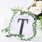 Black decorative rhinestone letter "T" with floral accents.