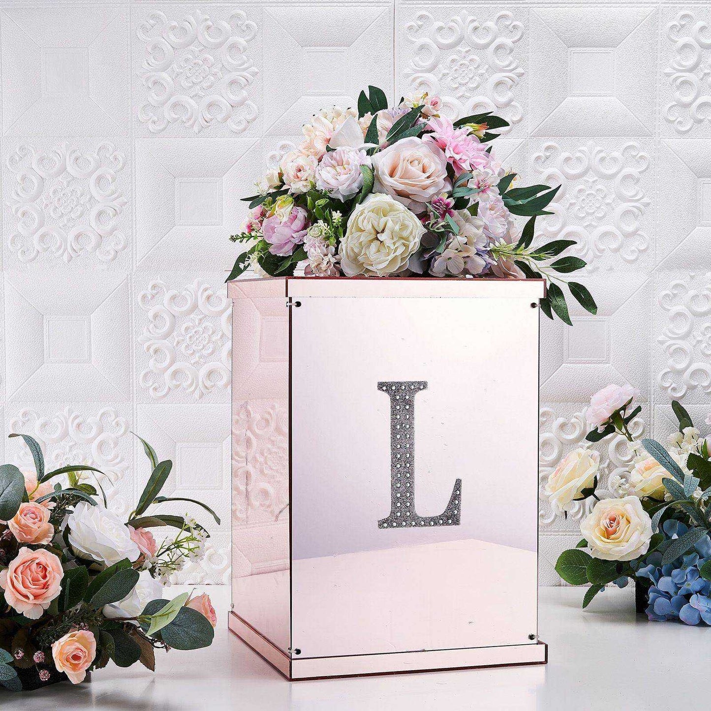 Silver rhinestone letter "L" decorative sticker on a mirrored box with floral arrangement.