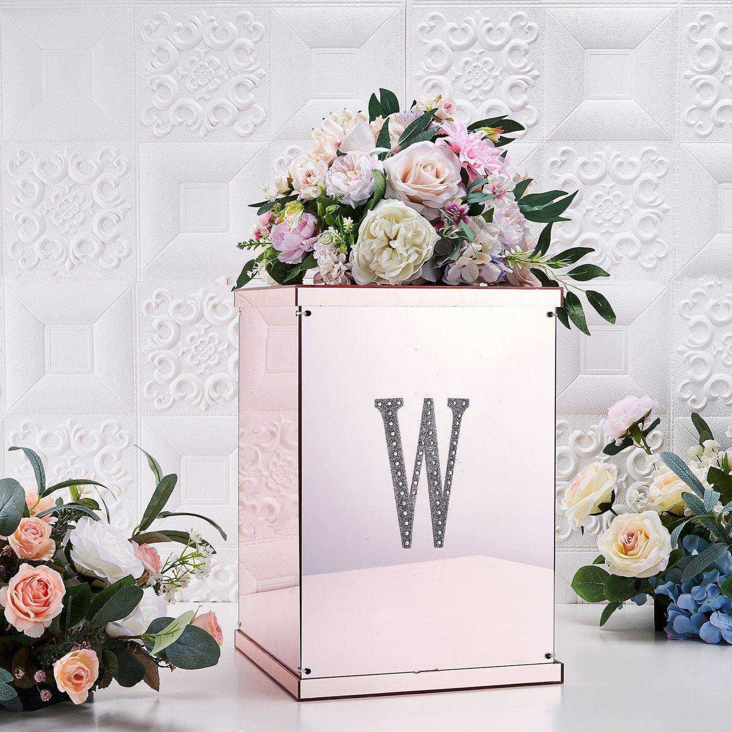 Silver decorative rhinestone letter "W" on a floral arrangement.