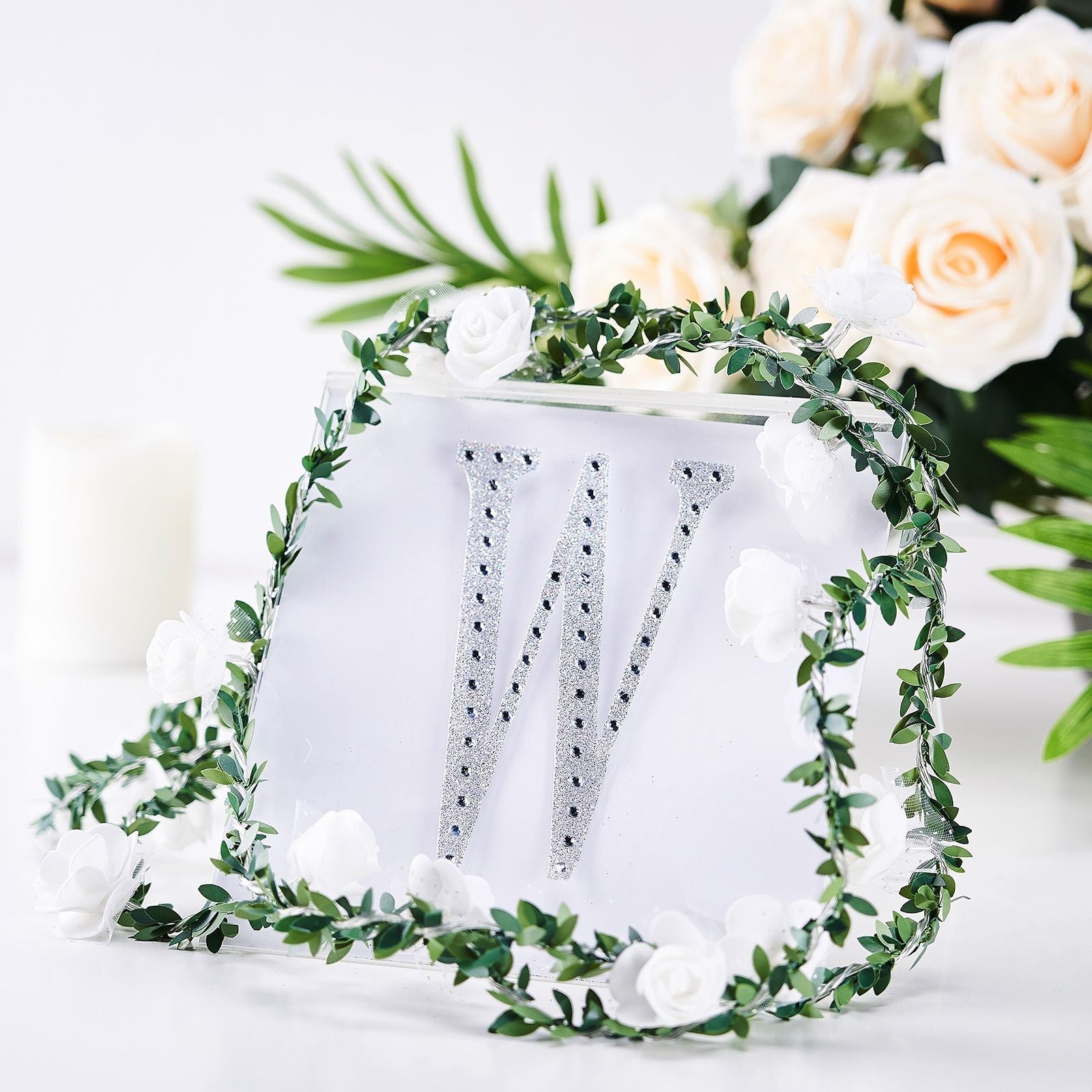 Silver decorative rhinestone letter "W" with floral accents.