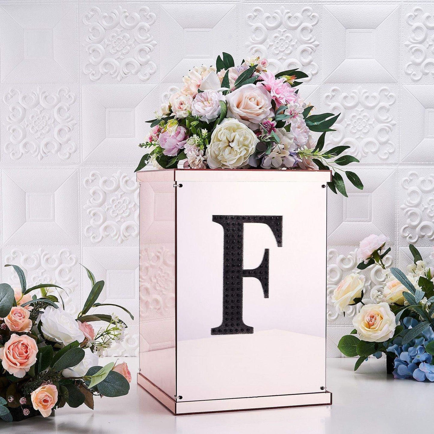 Black decorative rhinestone letter "F" on a floral arrangement.