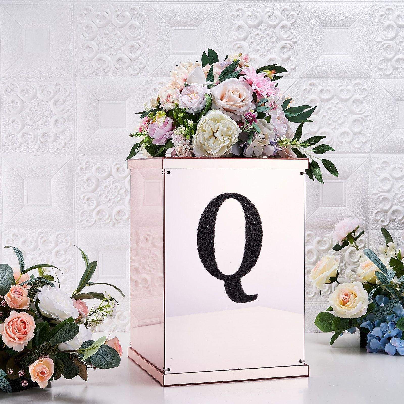 Black decorative rhinestone letter "Q" with floral arrangement.