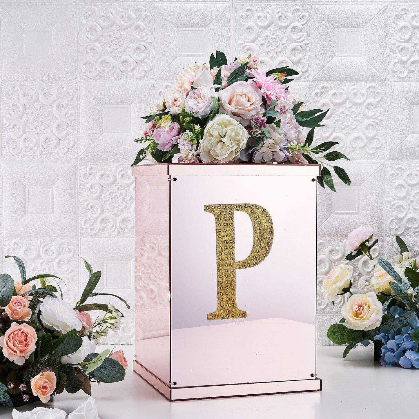 Gold decorative rhinestone letter "P" on a floral display.