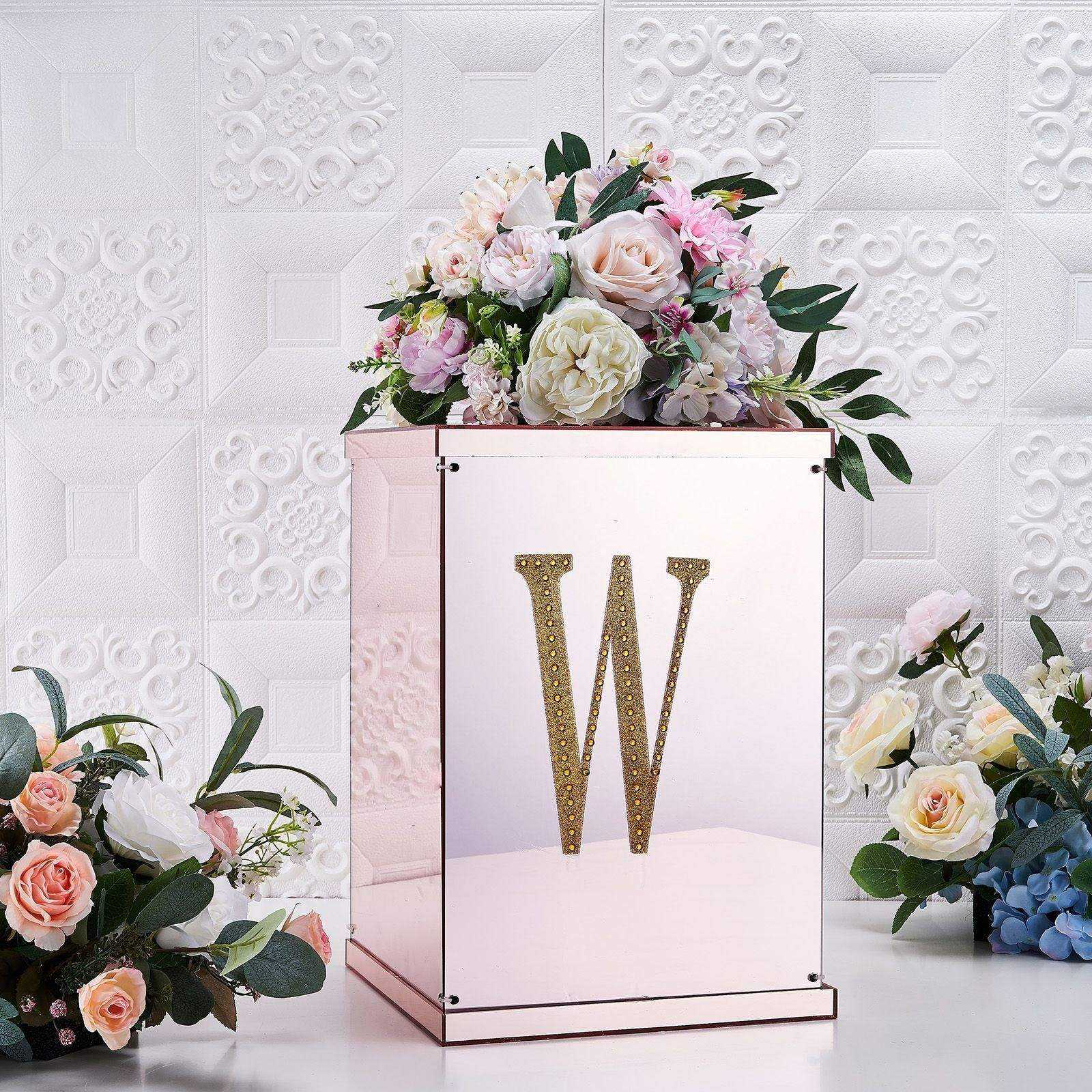 Gold decorative rhinestone letter "W" on a floral arrangement.
