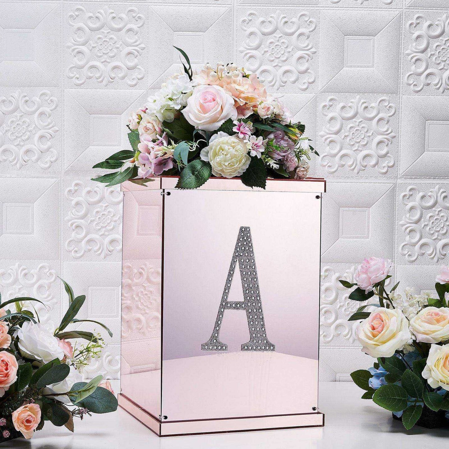 Silver decorative rhinestone letter "A" on a mirrored box with flowers.