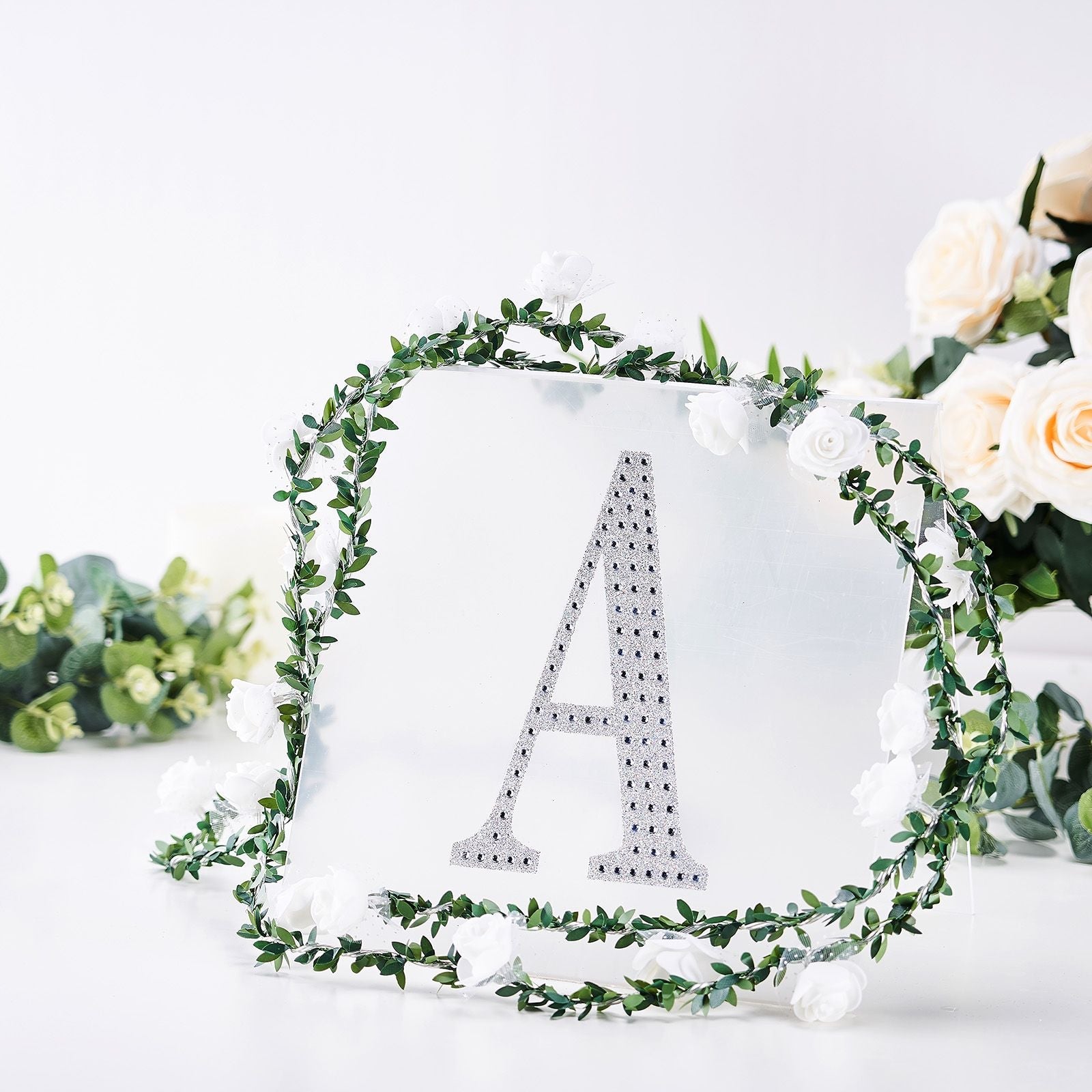 Silver decorative rhinestone letter "A" surrounded by floral accents.