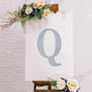 Silver rhinestone letter "Q" sticker on a decorated canvas.
