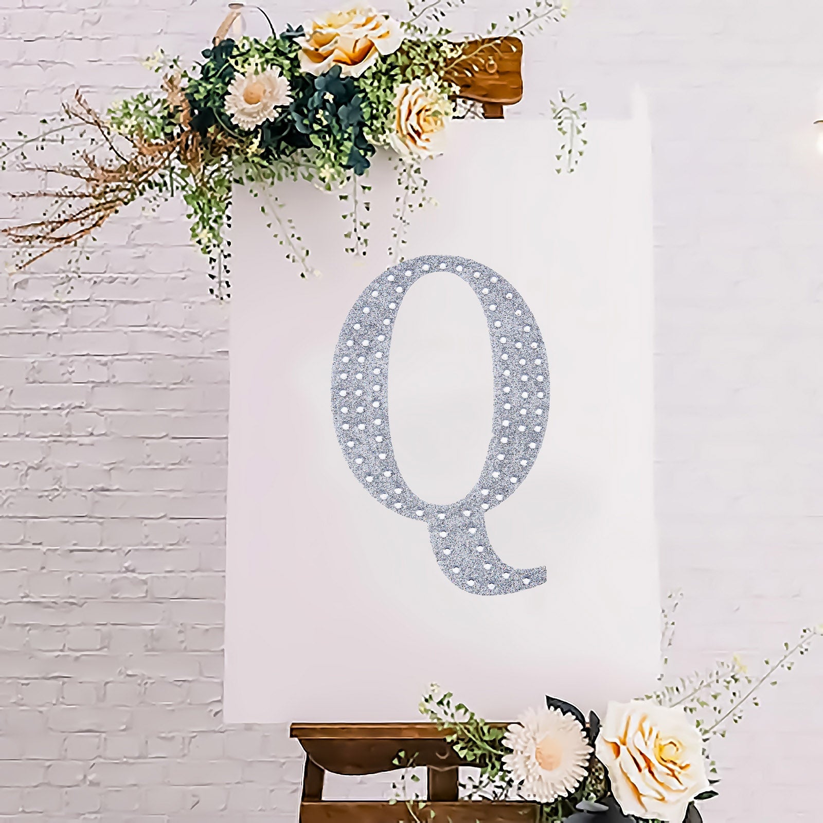 Silver rhinestone letter "Q" sticker on a decorated canvas.