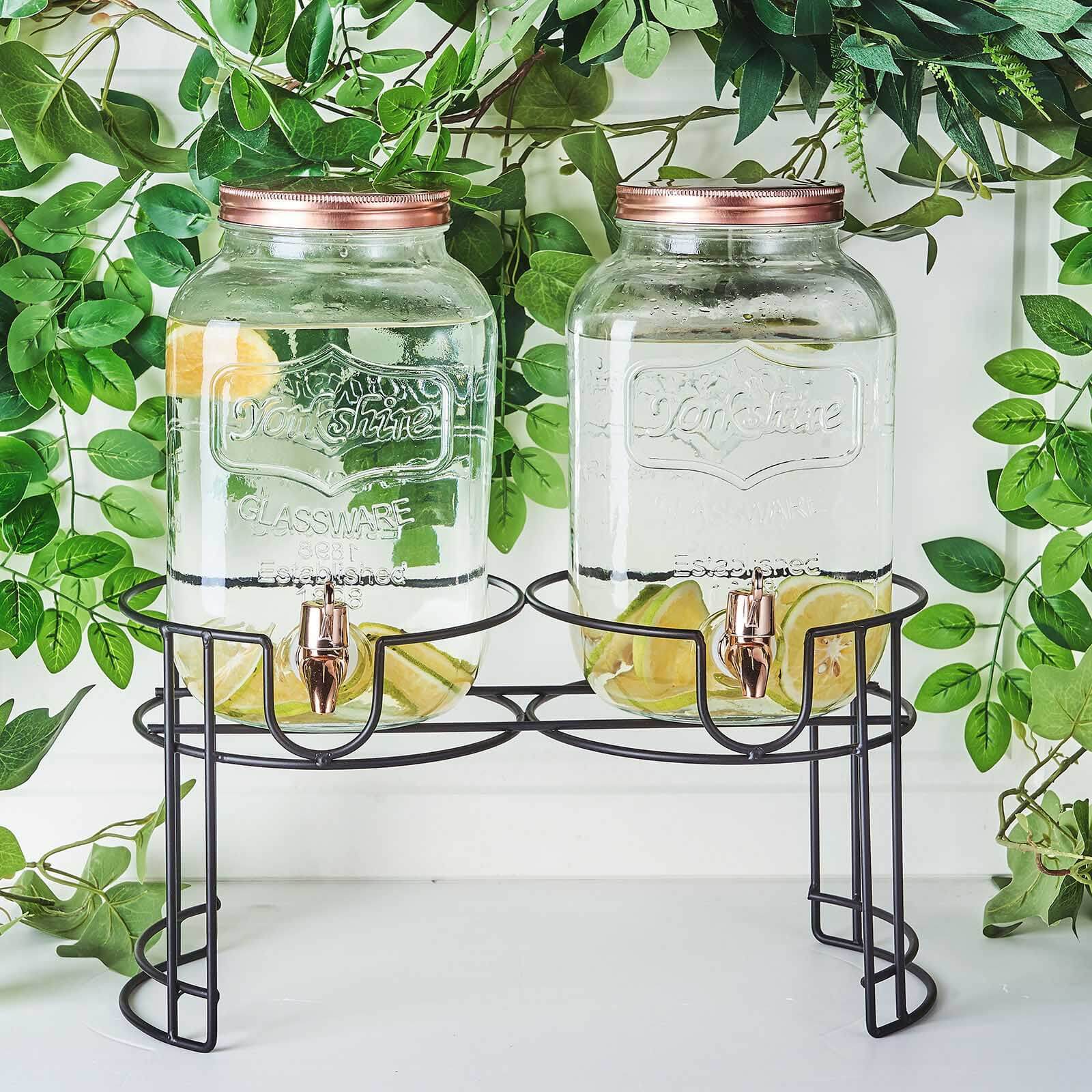 Clear dual gallon glass jars dispenser with rose gold lids.