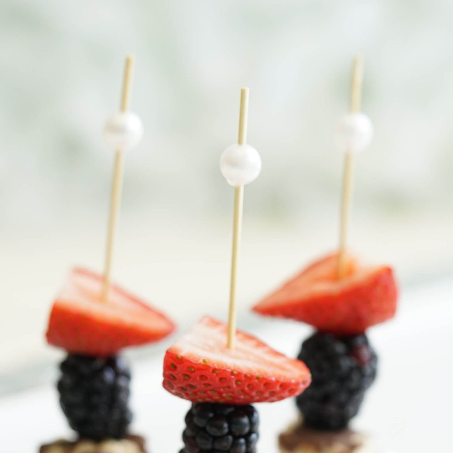 Natural pearl bamboo skewers with strawberries and blackberries.