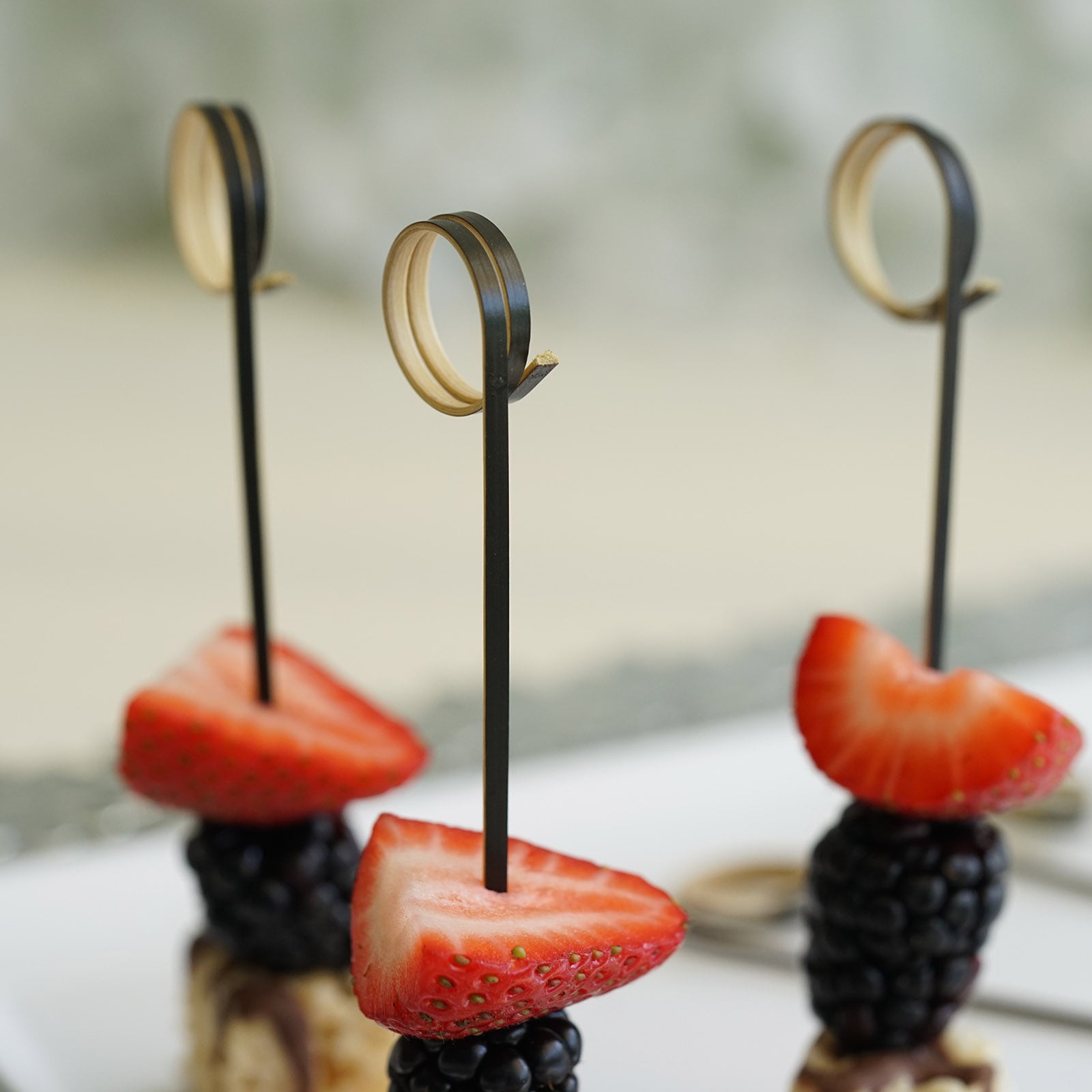 Eco-friendly black loop ring cocktail picks with decorative bamboo tops.