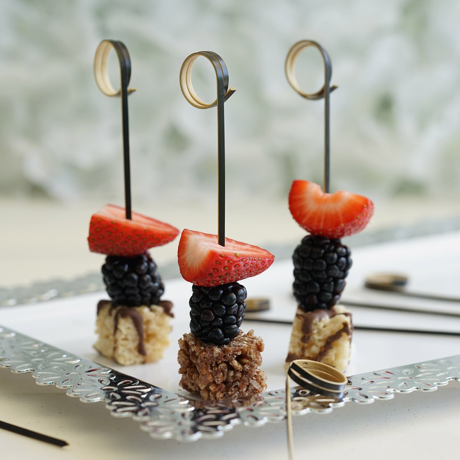 Eco-friendly black loop ring party picks with fruit on a decorative platter.