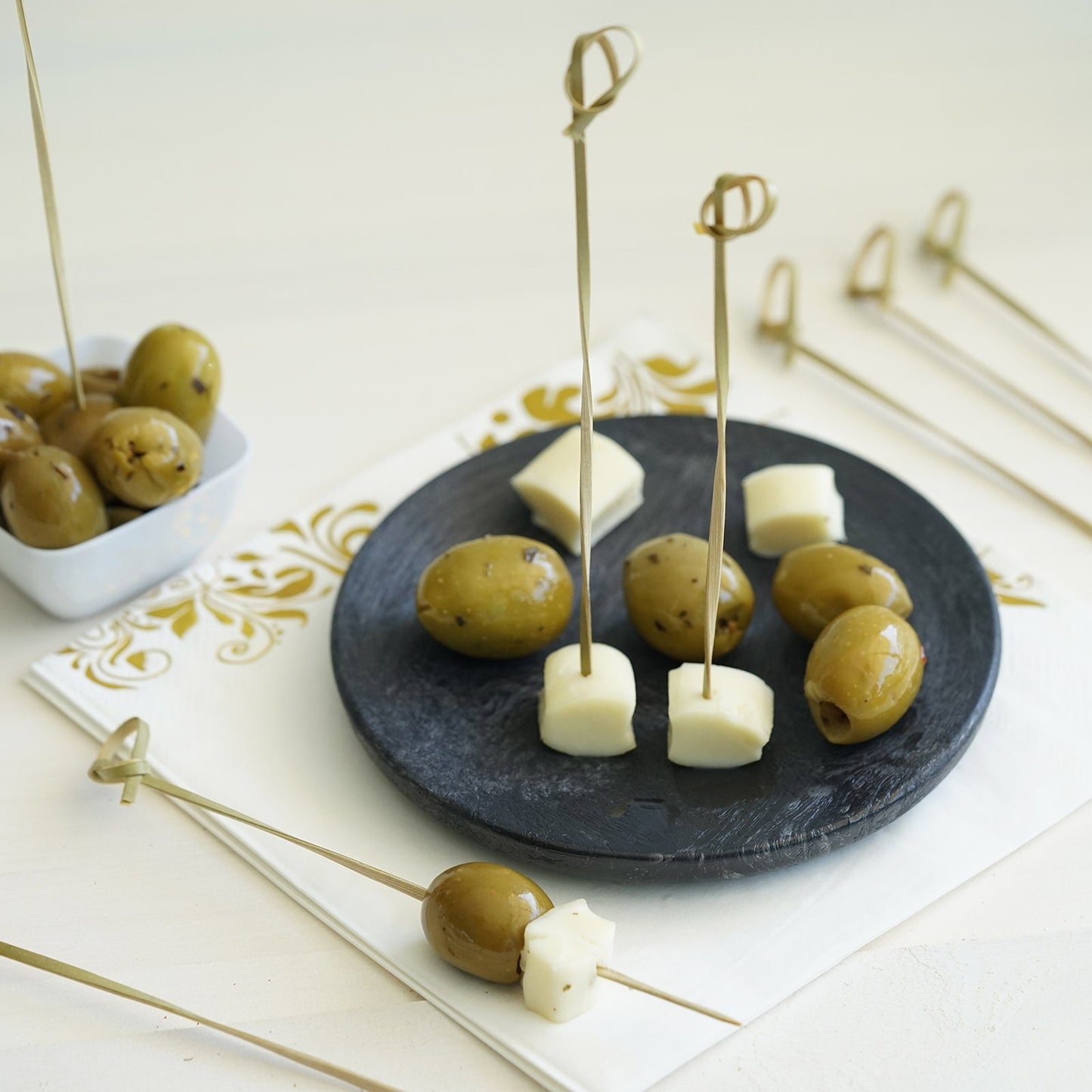 Eco-friendly bamboo cocktail sticks with decorative tops on a black plate.