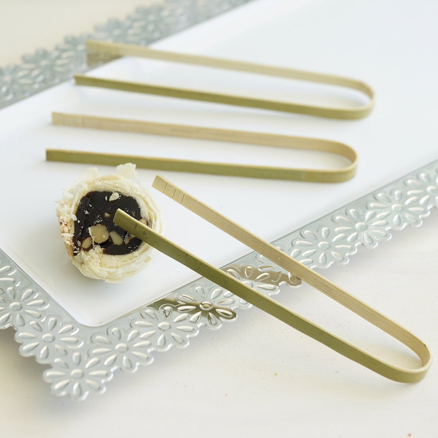 Eco-friendly natural bamboo wooden tongs on a serving platter.