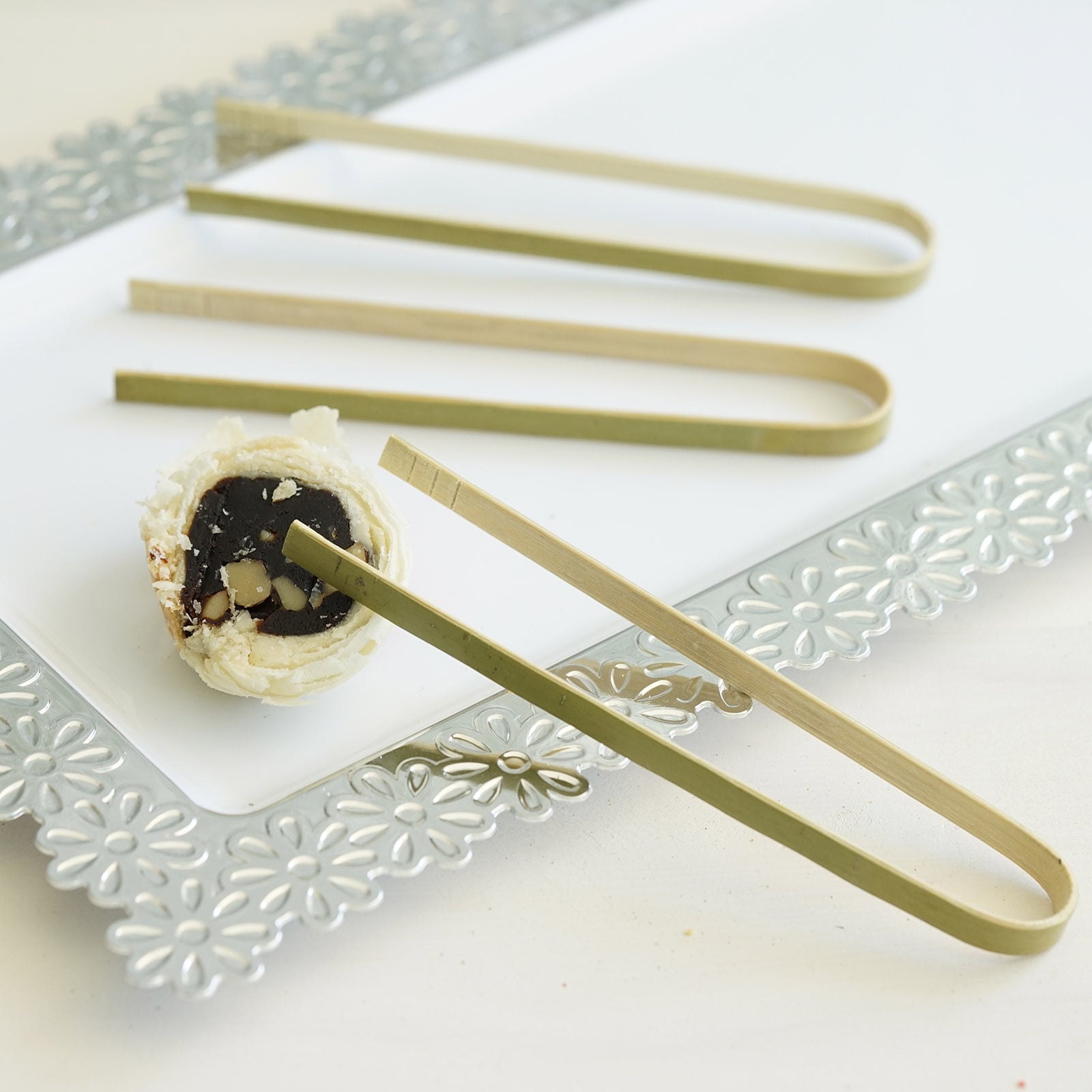 Eco-friendly natural bamboo wooden tongs on a serving platter.