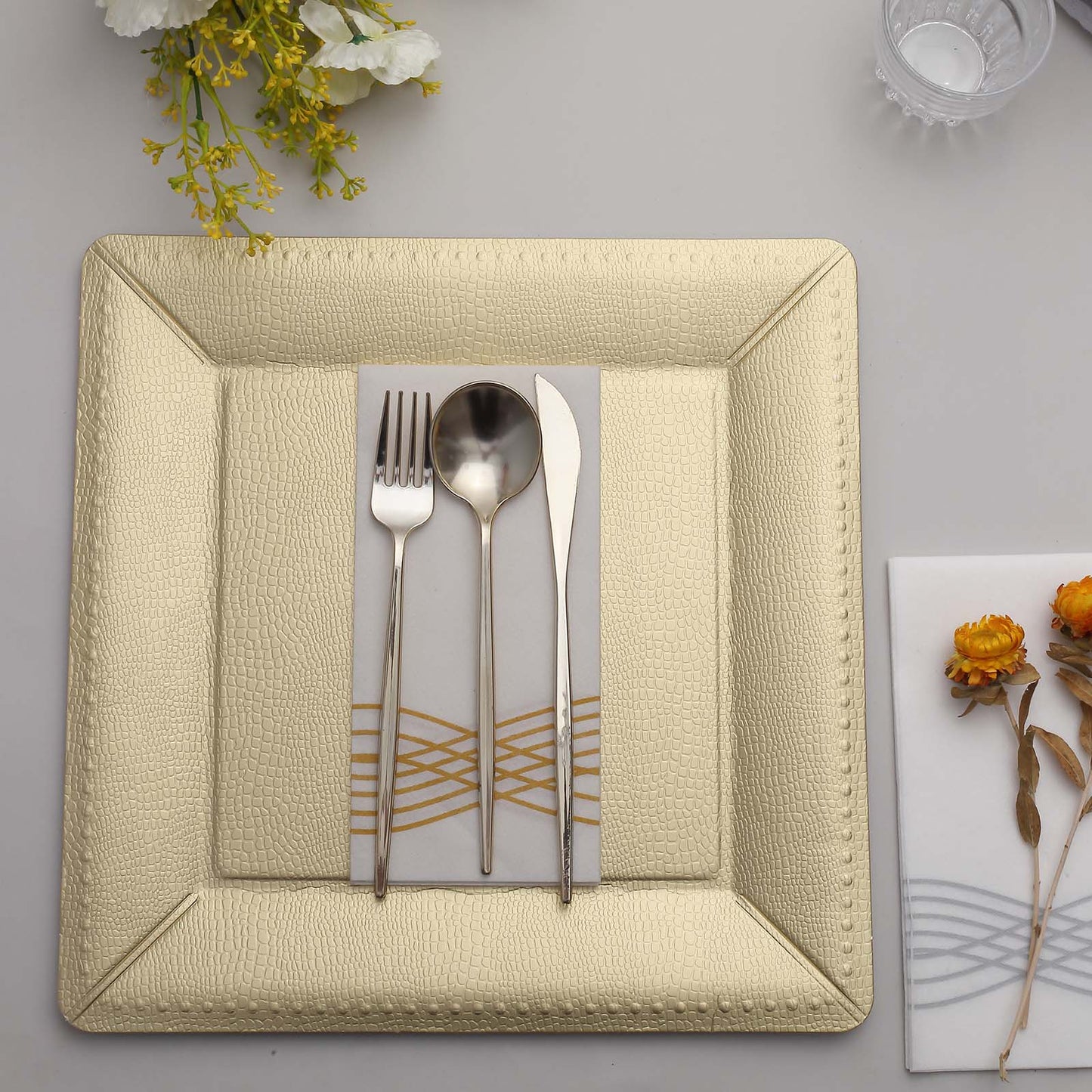 Champagne textured square serving tray with utensils on a table setting.