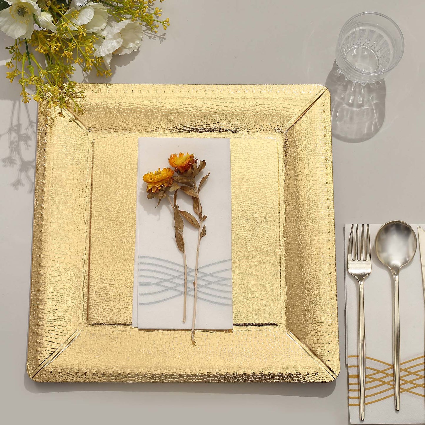 Gold textured disposable square serving tray with a floral decoration.