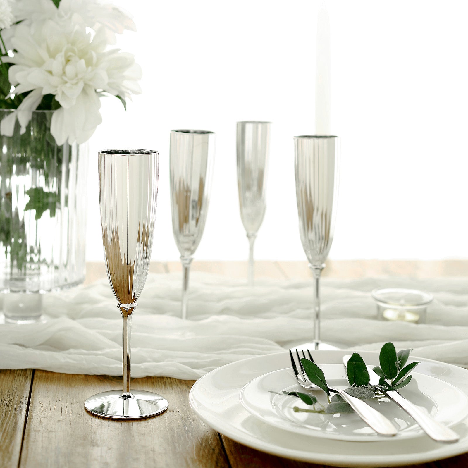 Silver 5oz disposable champagne flutes in an elegant setting.