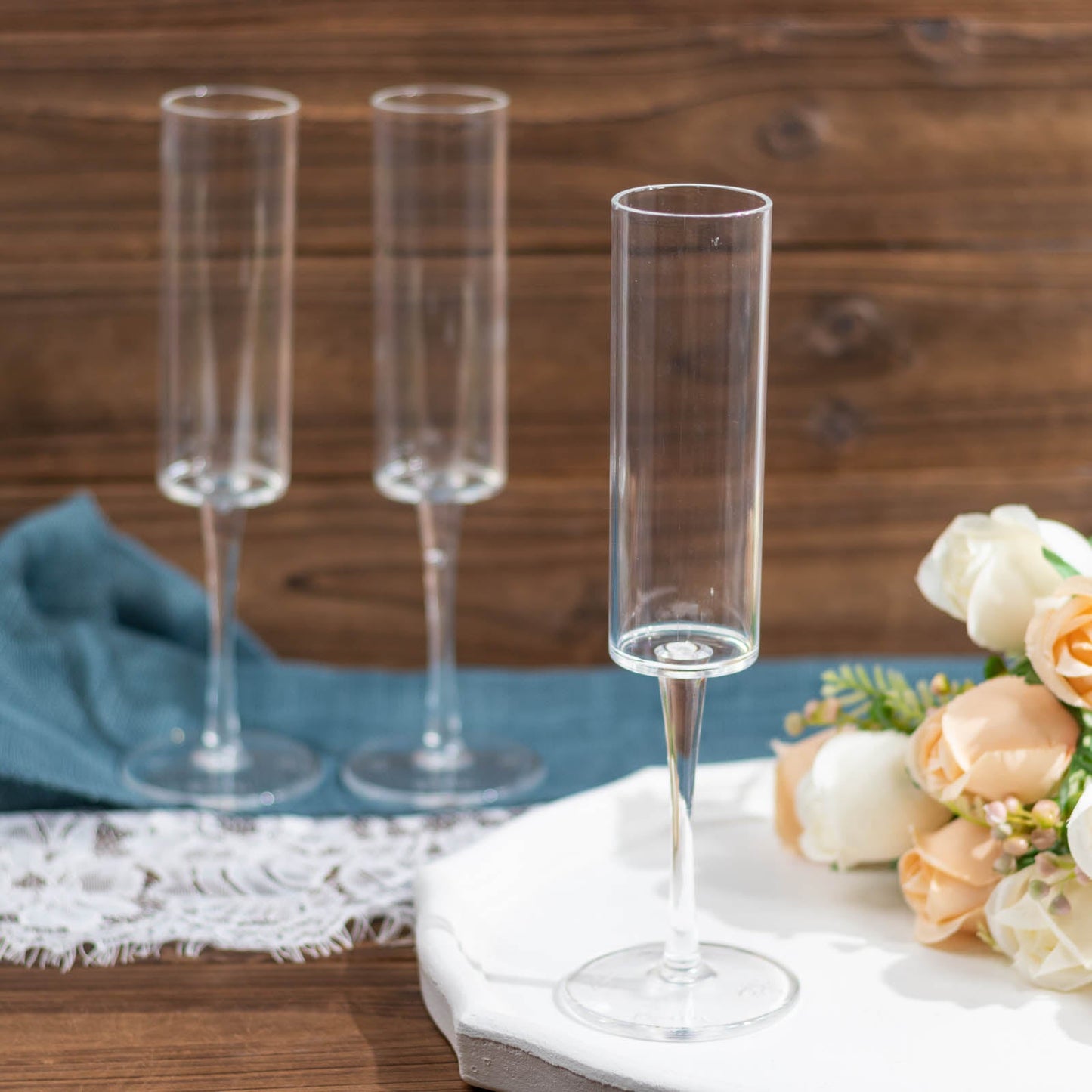 Clear reusable plastic champagne flute glasses in cylindrical shape.