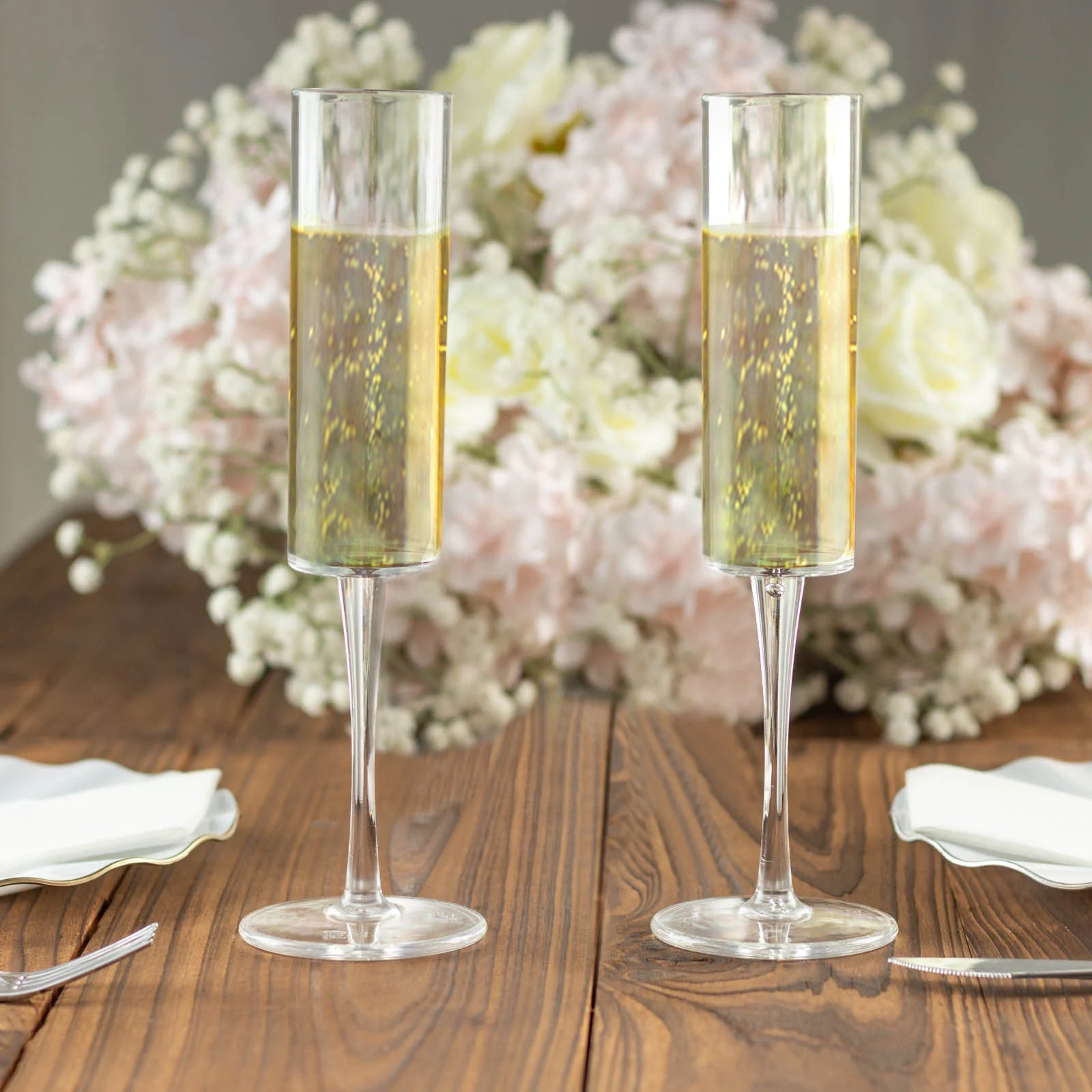 Clear reusable plastic champagne flute glasses in cylindrical shape.