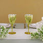 Gold disposable wine glasses on a table with flowers.