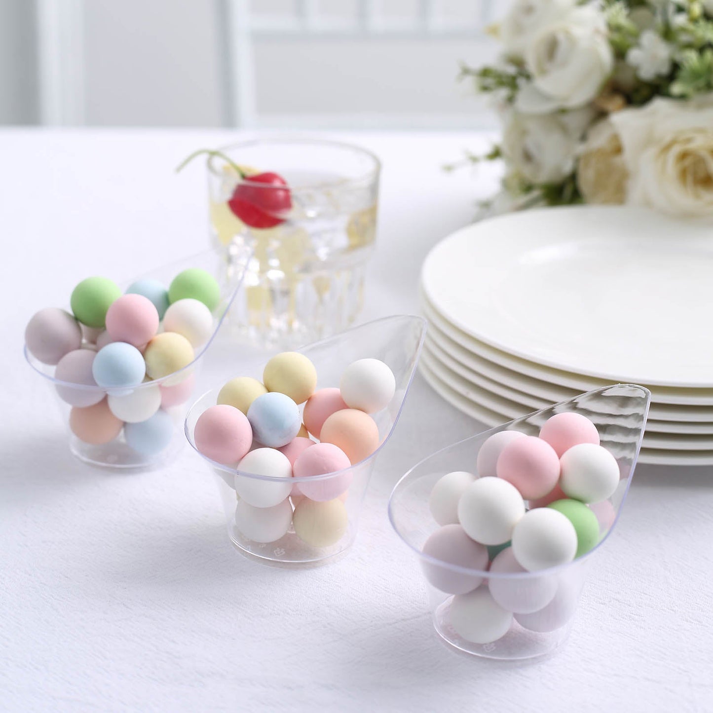 Clear mini disposable teardrop dessert cups filled with pastel candies.