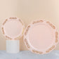 Blush pink round plastic appetizer plates with gold embossed scalloped edges.