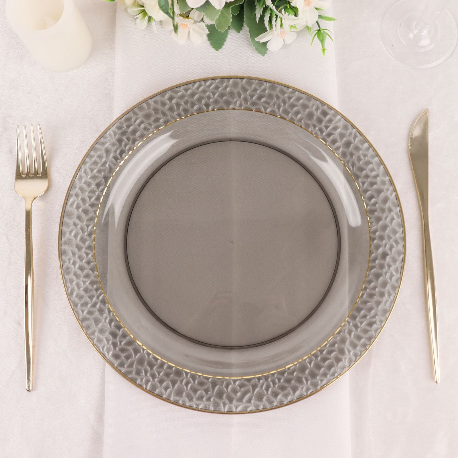 Opaque black hammered design plate with gold rim on a table setting.